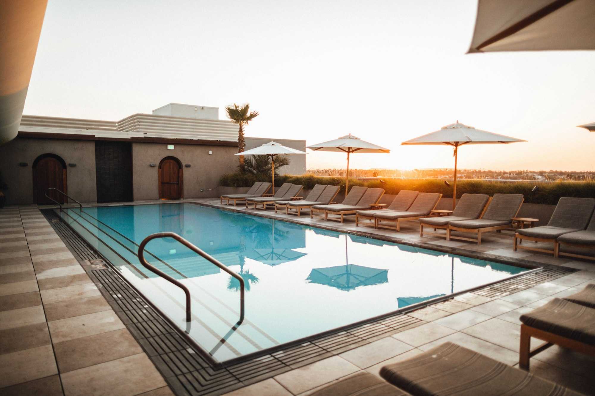 Piscine en couloir sur une terrasse au coucher du soleil, bordée de transats