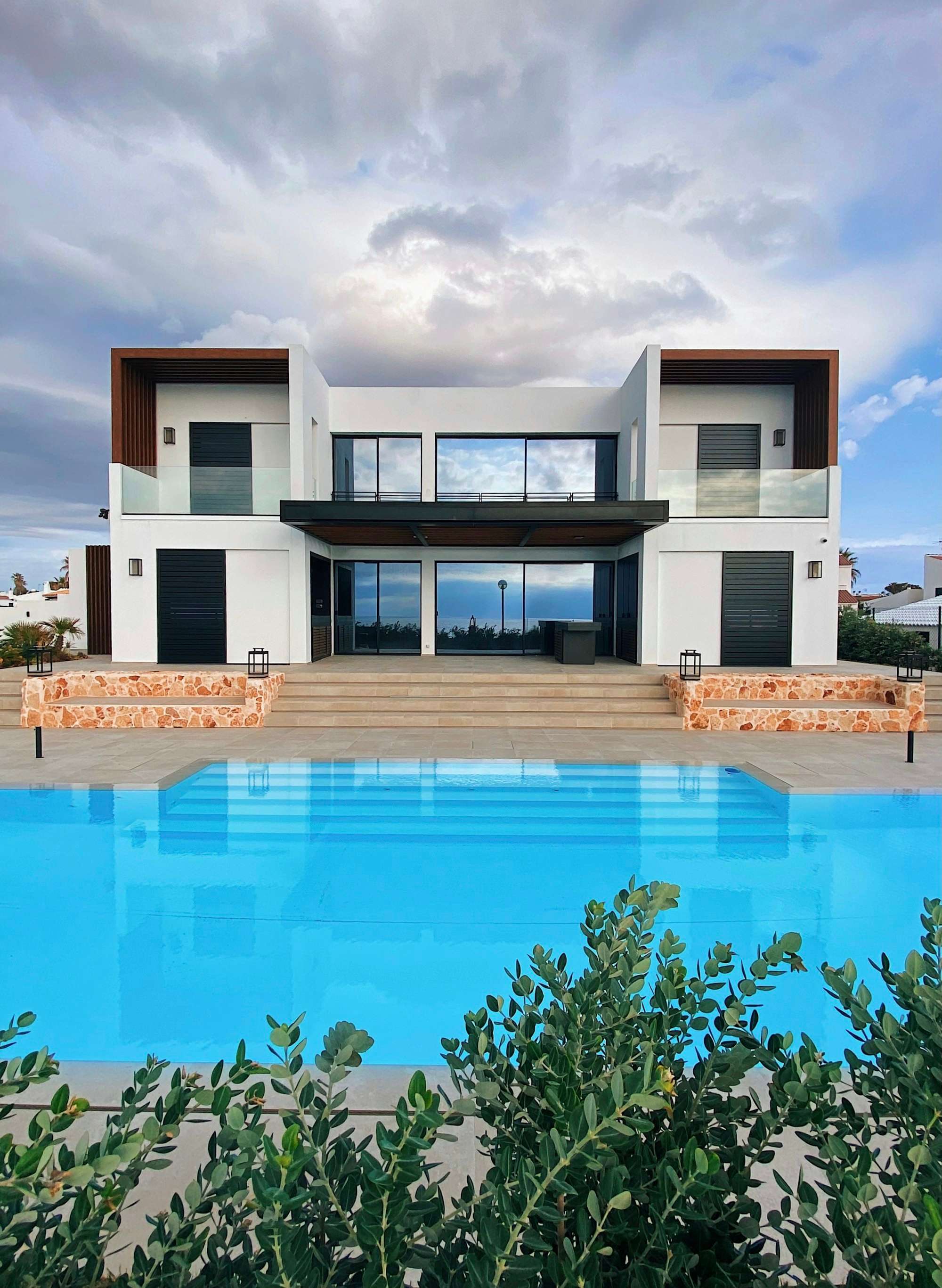 Grande piscine à débordement devant une villa contemporaine aux larges baies vitrées