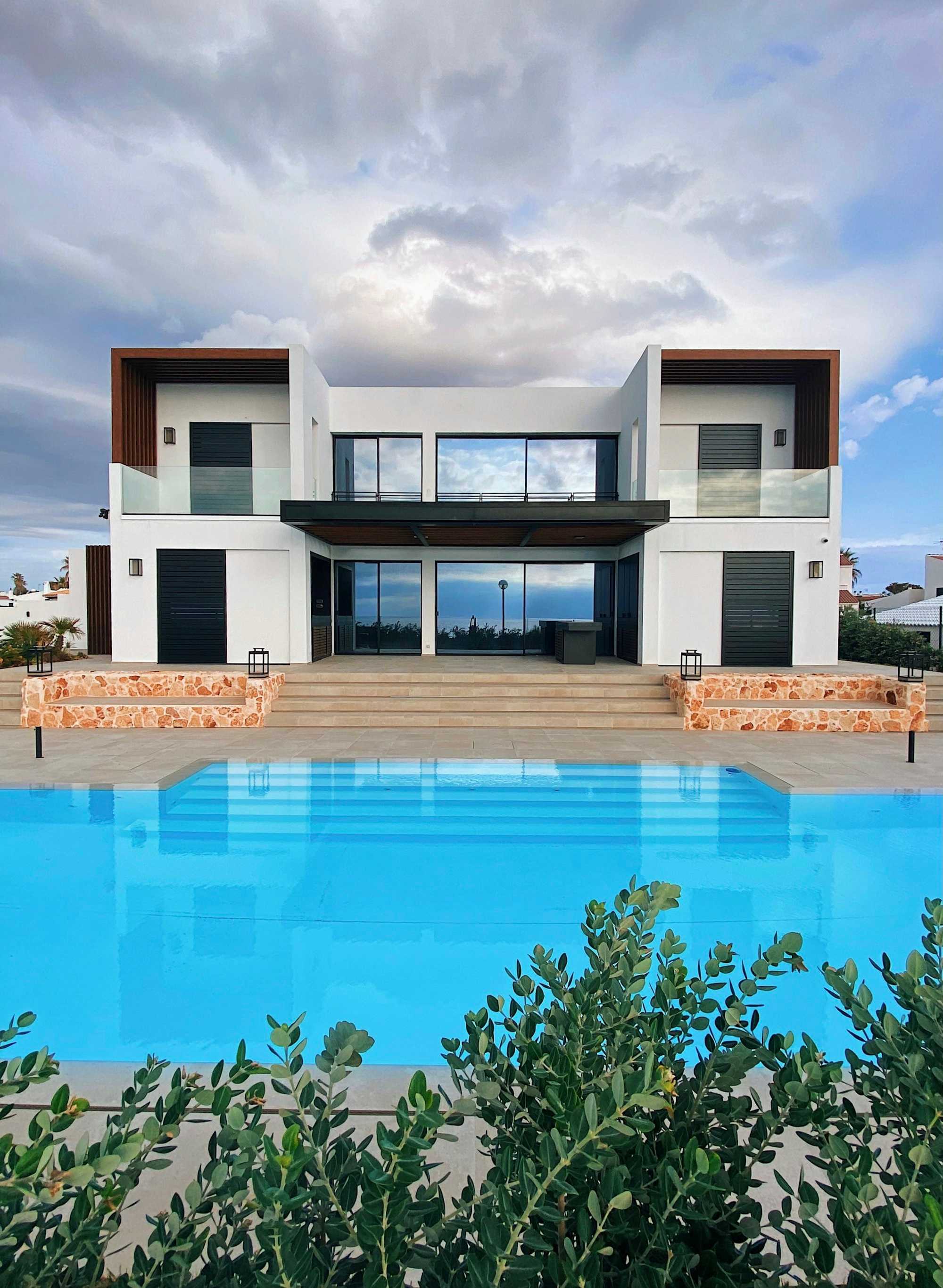 Grande piscine à débordement devant une villa contemporaine aux larges baies vitrées
